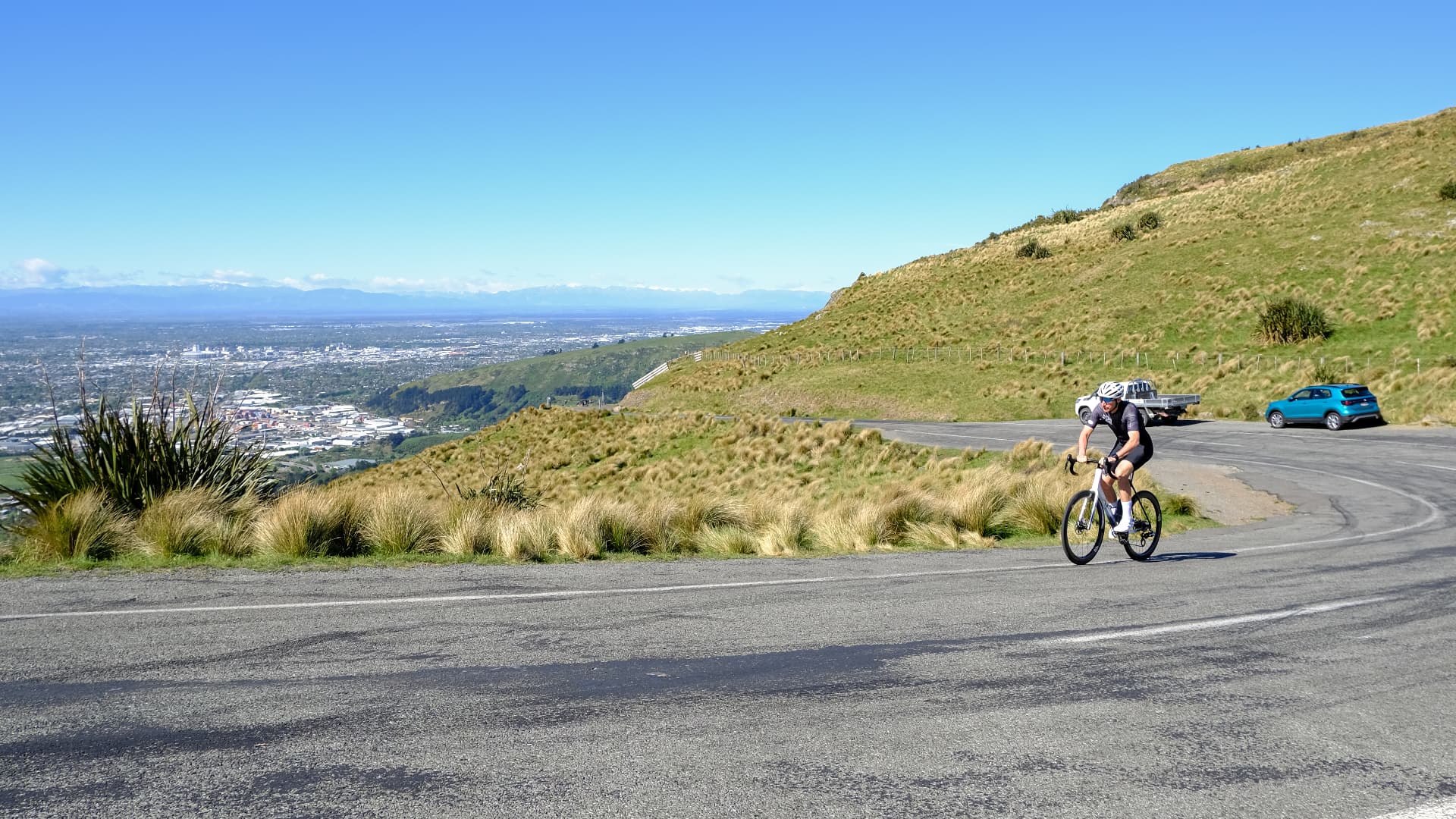 Rider climbing a hill road above the Canterbury plains on a bike fitted with Duo wheels